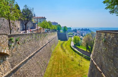 Citta Alta konutları Vialle delle Mura sokağı ile korunmuş ortaçağ surları ve tepe yamacındaki yemyeşil bahar bahçeleri, Bergamo, İtalya