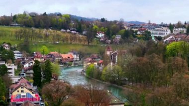 İsviçre 'nin Bern şehrinin tarihi ve modern konutlarıyla Aare Nehri' nin yamaçlı yeşil bankaları.