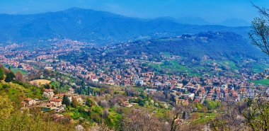 San Vigilio Tepesi 'nin tepesinden yeşil panoramik vadiler ve dağlar, uzun yeşil ağaçlarla kaplı, Bergamo, İtalya