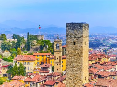 Bergamo Alta çatıları, selvi dolu yemyeşil park, Rocca di Bergamo kalesi, uzun taş Torre del Gombito ve arka planda Citta Bassa (aşağı kasaba), İtalya