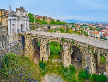 Iconic Porta San Giacomo gate and flowering spring park, located at the foot of medieval ramparts of Bergamo Alta, Italy clipart