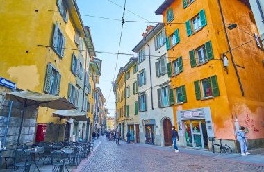 BERGAMO, İtalya - 7 Nisan 2022 Via Sant 'Alessandro' da turist dükkanları ve restoranları olan eski yoğun renkli evler hattı, Bergamo, İtalya