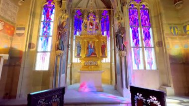 Heykeltraş edilmiş sunağı, vitray camları, taş duvarları ve boyanmış kasası olan eski kasaba kilisesinin dikey manzarası, Prag, Çek