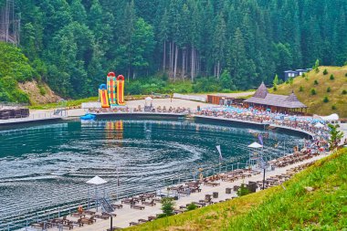 Bukovel, Karpatlar, Ukrayna 'daki Molodist Gölü' nün etrafındaki tahta güneşlikler.