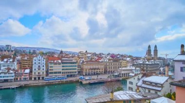 Hızlı akan bulutları, Limmat Nehri 'ni, mavi tramvaylı Limmatquai' yi, tarihi konak evlerini, karlı çatılarını, Grossmunster 'ın çan kulelerini, Niederdorf Mahallesi' ndeki Predigerkirche Kilisesi 'ni ve arka plandaki Alpleri, İsviçre