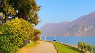 Lugano Gölü 'ndeki pitoresk Park Villa Heleneum' da palmiye ağaçları, çiçek açan kamelya çalıları, bambu çalılıkları, antik sütunlar ve sallanan yatlar, Lugano, İsviçre