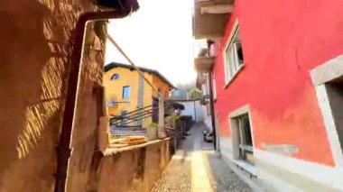Ronco sopra Ascona 'nın dar, dolambaçlı sokaklarında, Maggiore Gölü ve Alp manzarası, Ticino, İsviçre' de bulunan Maggiore Gölü ve Alp Parkı 'nı gözlemleyen renkli vintage evler boyunca zaman çizelgesi yürür.