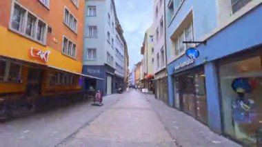ZURICH, SWitzERLAND - 3 Nisan 2022: Eski kasaba Niederdorfstrasse Caddesi 'nde eski evler, dükkanlar, kafeler ile yürür; Limmatquai Limmat Nehri setine 3 Nisan' da Zürih 'te döner