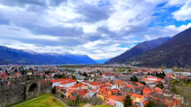 Vadideki eski Bellinzona kasabasında hızla akan bulutlar, dağ yamacındaki Montebello Kalesi 'nin avlusu ve arka plandaki Alpler, Ticino, İsviçre