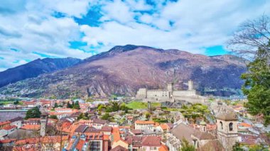 Bellinzona 'nın manzaralı dağ manzarası, eski kasaba çatıları, tepenin üstünde ortaçağ Castelgrande' si ve arka planında hızlı koşan bulutlar ve dağ yamaçlarında gölgeler, İsviçre