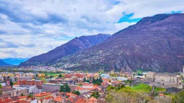 Alpler, karlı tepeler, akan bulutlar, kırmızı şehir çatıları, siyah Castelgrande kalesi ve İsviçre 'nin Montebello kalesinin surları manzaralı Bellinzona Panoraması.