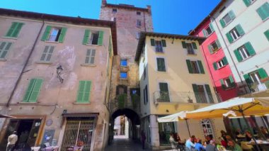 Ortaçağ pejmürde Via dei Musei Caddesi 'nin panoramasında açık hava restoranları, küçük kafeler ve barlar, Brescia, İtalya