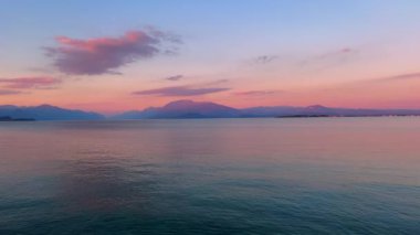 The picturesque sunset over Lake Garda with scenic rippled surface and silhouettes of Garda Prealps in the background, Desenzano del Garda, Italy