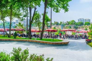 Arka planda bir açık hava restoranı olan güzel yeşil gölgeli Mermerli Parkı, Antalya, Türkiye