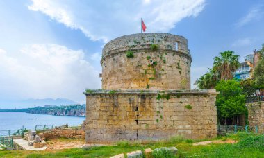 The stone ruins of historic Hidirlik Tower against the rocky coast of Antalya, Turkey clipart