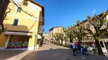 Via San Salvatore ve Piazza Porto Valentino Meydanı 'nın Panorama' sı Sirmione 'de tarihi evleri, yayılmış ağaçlar ve turist restoranları, İtalya