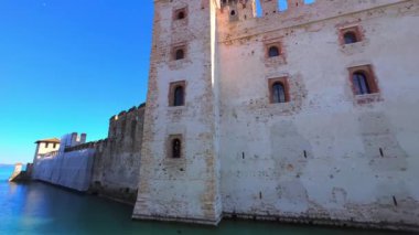 Panoramic view of historic Scaligero Caslte surrounded with a dug moat, located amid the small old town of Sirmione on the bank of Lake Garda, Italy