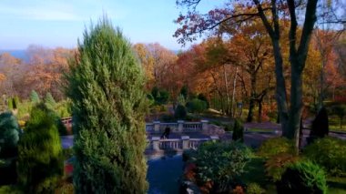 Tepedeki süs parkının panoraması ve sarı sonbahar ormanı olan ahşap bir Honka kulüp evi ve ufukta Dnieper Nehri, Mezhyhirya, Novi Petrivtsi, Ukrayna