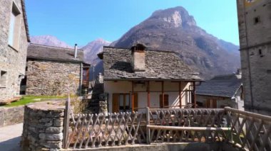 Santa Maria Lauretana Kilisesi 'nin çan kulesi ve taş kubbeleri Sonogno, Valle Verzasca, İsviçre' nin yaşayan taş evlerinin arkasında görülmektedir.