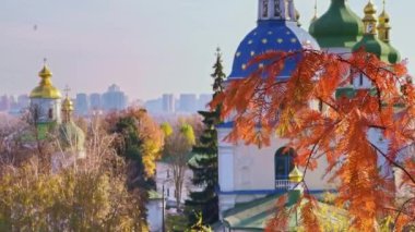 The red larch branch in front of the medieval Vydubychi Monastery domes with golden tops and stars, Kyiv, Ukraine