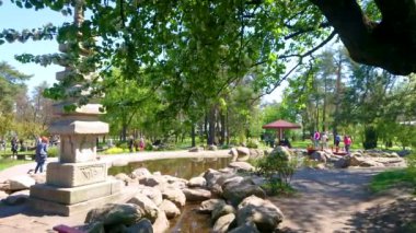 KYIV, UKRAINE - 11 Mayıs 2021: Japon çok katlı Budist Pagoda manzarasının ve Kyoto Park manzaralı ağacın arkasındaki havuzun tadını çıkarın.