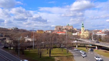 Dobrentei Meydanı 'nda yeşil park ve yoğun yollar İskenderiyeli Aziz Catherine Kilisesi' nin yüksek çan kulesi ve Budapeşte, Macaristan 'daki Castle Hill' in tepesinde Buda Kalesi.