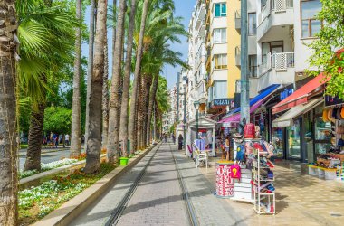 ANTALYA, TURKEY - 13 Mayıs 2017: Atatürk Bulvarı, Barbaros, Antalya, Türkiye 'deki turist dükkanları boyunca yeşil palmiyeler ve renkli çiçek yatakları