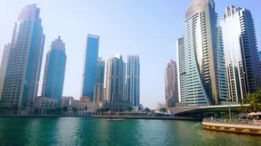 DUBAI, BAE - 2 Mart 2020 Dubai Marina manzarasının tadını çıkarın yüzen turist tekneleri ve karşı kıyıdaki modern gökdelenlerle, 2 Mart 'ta Dubai' de