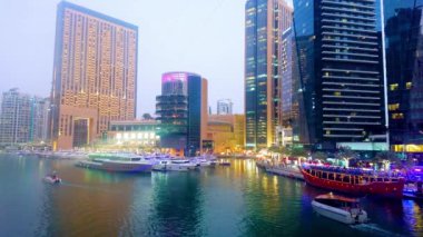 DUBAI, BAE - 2 Mart 2020: Alacakaranlıktaki Dubai Marina 'nın modern aydınlık binaları - Pier 7 restoran kompleksi, Marina AVM ve Dubai Marina Oteli bir yat kulübü ve ön planda bir iskele ile 2 Mart' ta Dubai