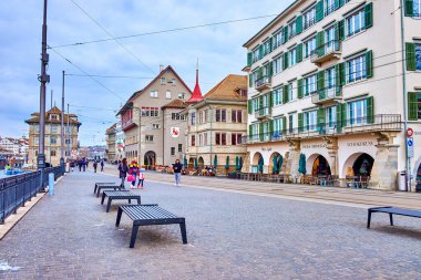 ZURICH, SWITZERLAND - APRIL 3, 2022: The pleasant resting area with benches on Limmatquai promenade, on April 3 in Zurich, Switzerland clipart