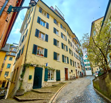 ZURİH, SWitzERLAND - 3 Nisan 2022: Zürih 'in ikonik silueti 3 Nisan' da İsviçre 'nin Zürih kentindeki Limmat Nehri panoramasının zeminine karşı kurulan Grossmunster ve Fraumunster kiliselerine sahip.
