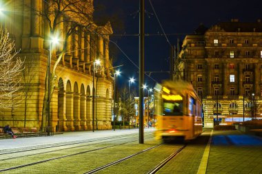 Budapeşte, Macaristan 'daki güzel, aydınlık binalar arasında Lajos Kossuth meydanındaki sarı tramvay yolculukları