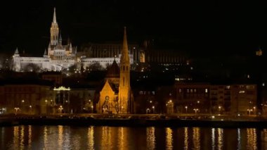 Karanlık gece gökyüzüne karşı Matthias Kilisesi ve Tuna Nehri kıyısındaki zarif Szilagyi Dezso Meydanı Kilisesi 'ne karşı Balıkçı Kalesi' ni aydınlattı.