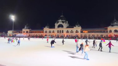 Aydınlatılmış Şehir Parkı Buz Pisti Panoraması 'nın arka planında tarihi bir pavyon, Budapeşte, Macaristan