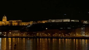 Buda Kalesi 'nin yanardöner binasiyla gece panoramasi Castle Hill' in tepesinde, Matthias Kilisesi 'nin yüksek çan kulesi ve Budapeşte, Macaristan' in karsisindaki nehrin karsisindaki Szilagui Dezso Meydanı Protestan Kilisesi ile Balıkçı Kalesi.