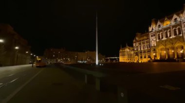 Tramvay, Parlamento, Budapeşte ve Macaristan 'ın aydınlık binası manzaralı karanlık gece boyunca Lajos Kossuth Meydanı boyunca ilerliyor.