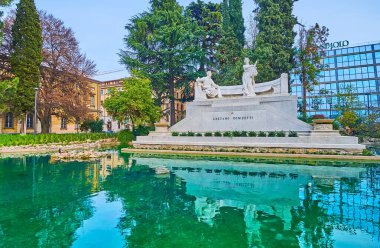 BERGAMO, İtalya - 7 Nisan 2022: Gaetano Donizetti 'nin beyaz zarif anıtı ve önündeki çeşme, Citta Bassa, Bergamo, İtalya