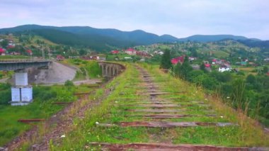 Yeşil dağlar ve Vorokhta, Karpatlar ve Ukrayna 'nın küçük evleri ile çevrili demiryolu köprü-viyadük kalıntıları.