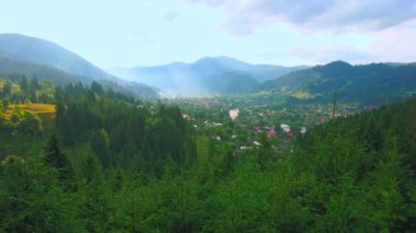 Güneş bulutların arasından parlıyor ve etrafındaki yeşil Verkhovyna ve Karpat Dağları vadisini aydınlatıyor, Ukrayna