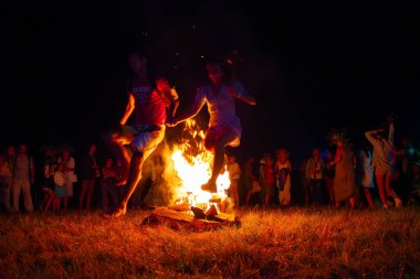 KOPACHIV, UKRAINE - 6 Temmuz 2021: Ukrayna 'daki Kyiv Rus Parkı' ndaki Ivana Kupala Gecesi kutlamasında genç bir çift ateşin üzerinden atladı