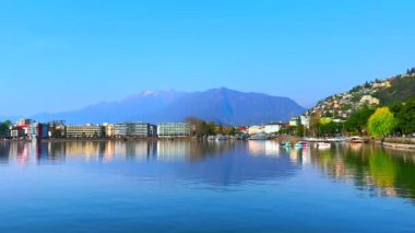 Aynaya benzeyen Maggiore Gölü yüzeyi ve arka planda puslu Alpler, Locarno, Ticino, İsviçre