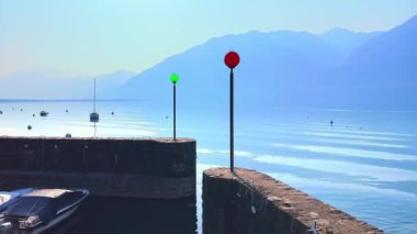 Maggiore Gölü 'nde küçük balıkçı tekneleri, puslu dağlar, yeşil park ve arka planda Muralto' nun eski kamaraları, Locarno, İsviçre
