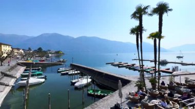 Lungolago 'dan (göl kenarı) Ascona limanının parlak mavi su yüzeyi ve puslu Alpler, Ticino, İsviçre