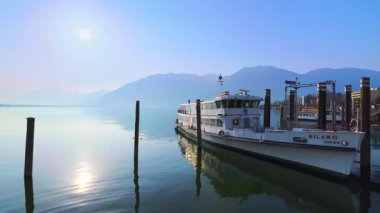 Maggiore Gölü 'nün puslu gündoğumu Alplere, Locarno' ya, Ticino 'ya, İsviçre' ye karşı demirli bir feribota bakıyor.