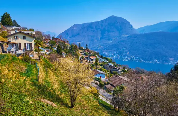 stock image The gentle mountain slope with small houses and flowering spring gardens of Carona, Ticino, Switzerland