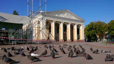 Mykola Hohol Müzikal-Dramatik Tiyatrosu (Nikolai Gogol), Poltava, Ukrayna 'nın önündeki güneşli yaya tiyatrosu meydanında güvercin sürüsü