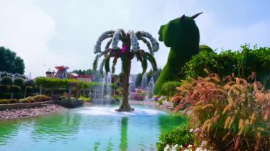 DUBAI, BAE - 5 Mart 2020: 5 Mart 'ta Dubai' de, Miracle Garden 'da palmiye ağacı şeklindeki fıskiyeyle süslenmiş, beyaz ve pembe petunyalarla kaplı resim göleti