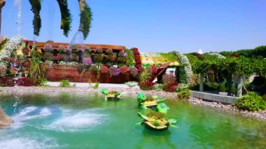 DUBAI, BAE - 5 Mart 2020: Kaplumbağa heykelleri ile süslenmiş, 5 Mart 'ta Dubai' de Miracle Garden 'da çiçek saksısı olarak hizmet veren, gölet ve çeşmeli panorama