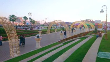 DUBAI, BAE - 5 Mart 2020: Dubai 'de yeşil çimenler ve ticaret pavyonlarıyla çevrili, Global Village Dubai' de ışıklandırılmış kemer yolu ile Panorama
