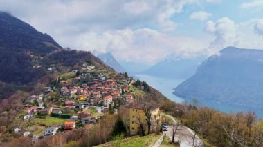 Monte Bre 'nin manzaralı yeşil yamacında eski Alp Bre köyünün renkli evleri Lugano Gölü ve dağlarına karşı Ticino, İsviçre